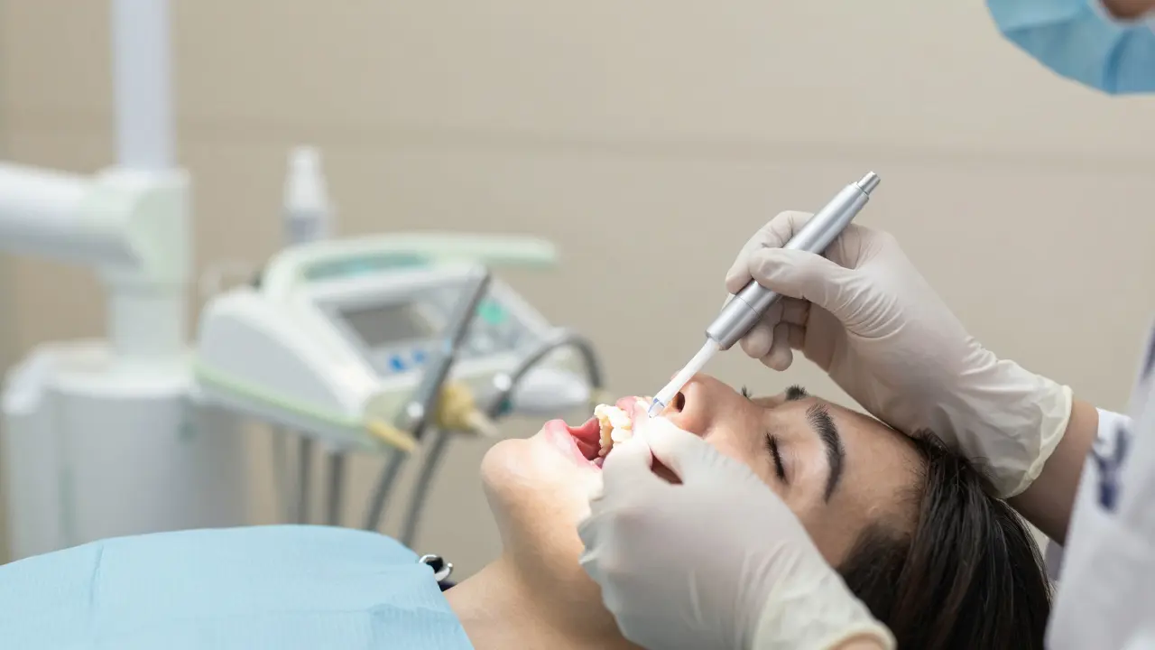 Zubní lékař aplikuje fluoridový lak na zuby pro úlevu od citlivosti